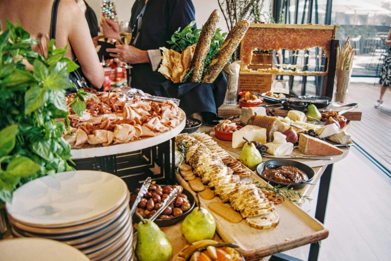 Reich gedeckter Catering-Tisch mit Aufschnitt, Käse, Oliven und Baguette bei einer Veranstaltung